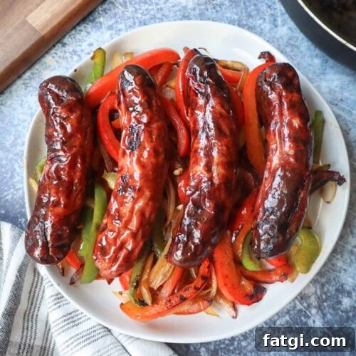 white plate with peppers onion and four air fryer chicken sausages
