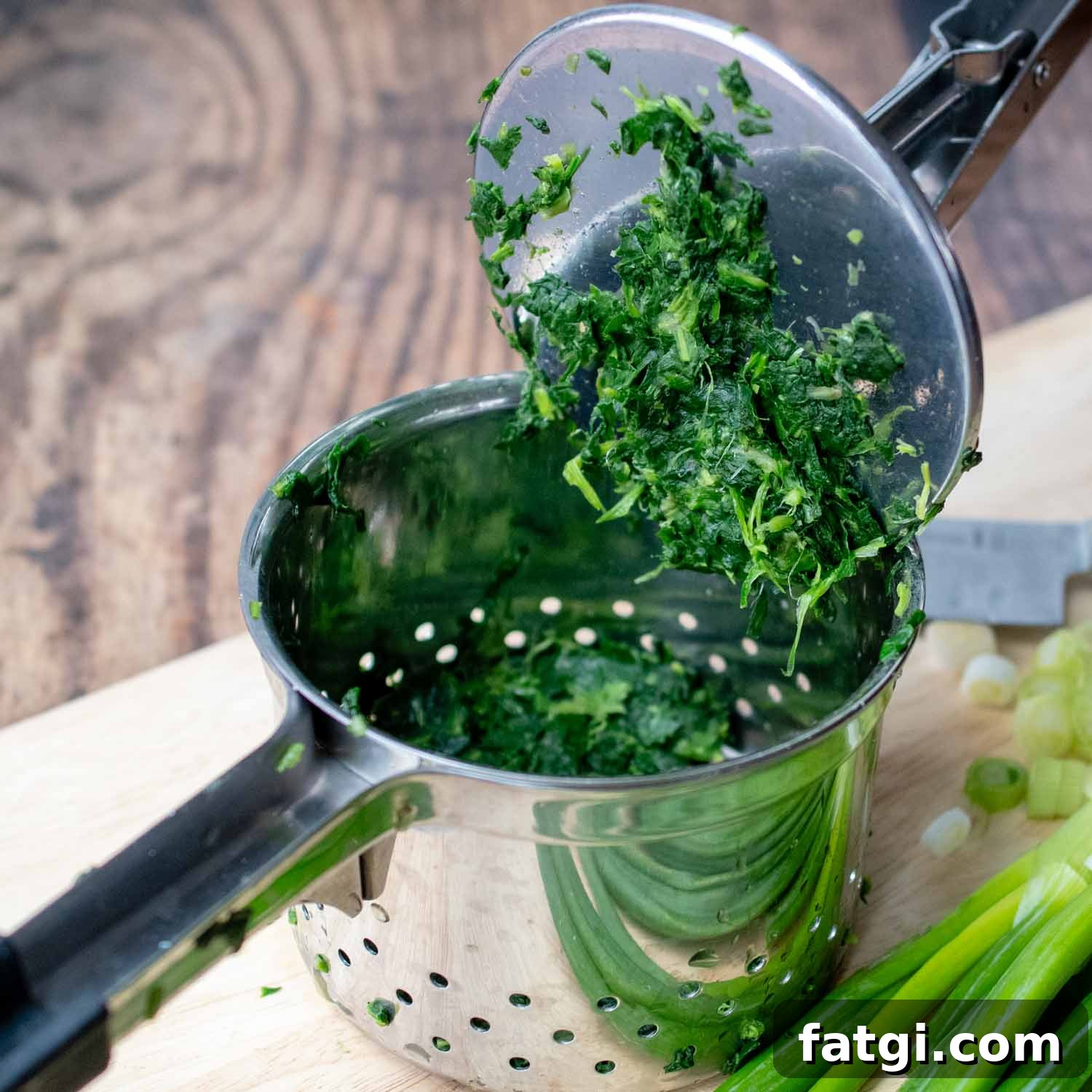 chopped spinach in a potato ricer.