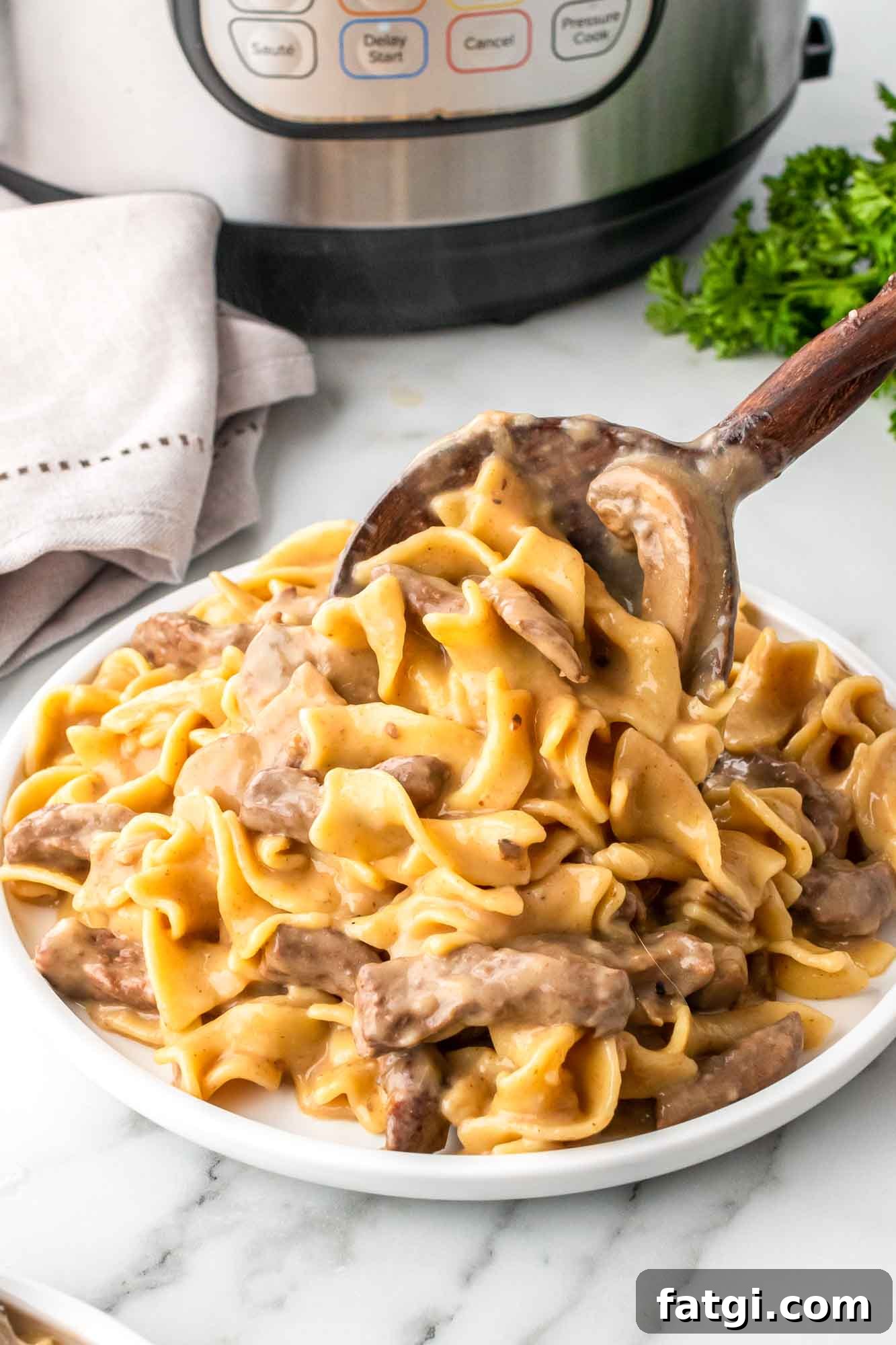 Instant Pot Beef Stroganoff with Tender Beef and Creamy Sauce 2 Creamy Beef Stroganoff cooked in an Instant Pot and served with a wooden spoon