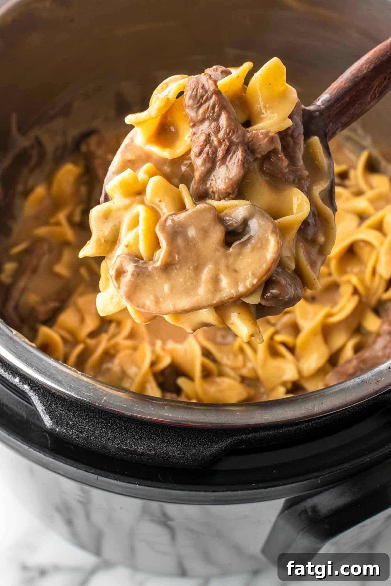 Instant Pot Beef Stroganoff with Tender Beef and Creamy Sauce 9 Close up of Beef Stroganoff on a wooded serving spoon