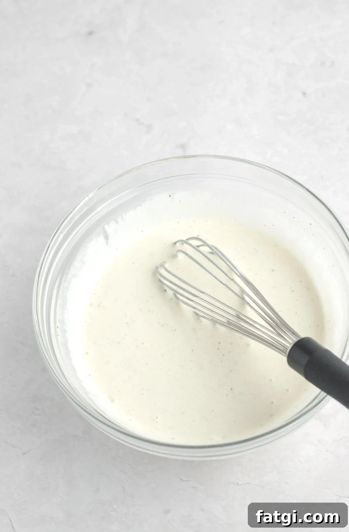 Chicken salad dressing in a bowl with a whisk.