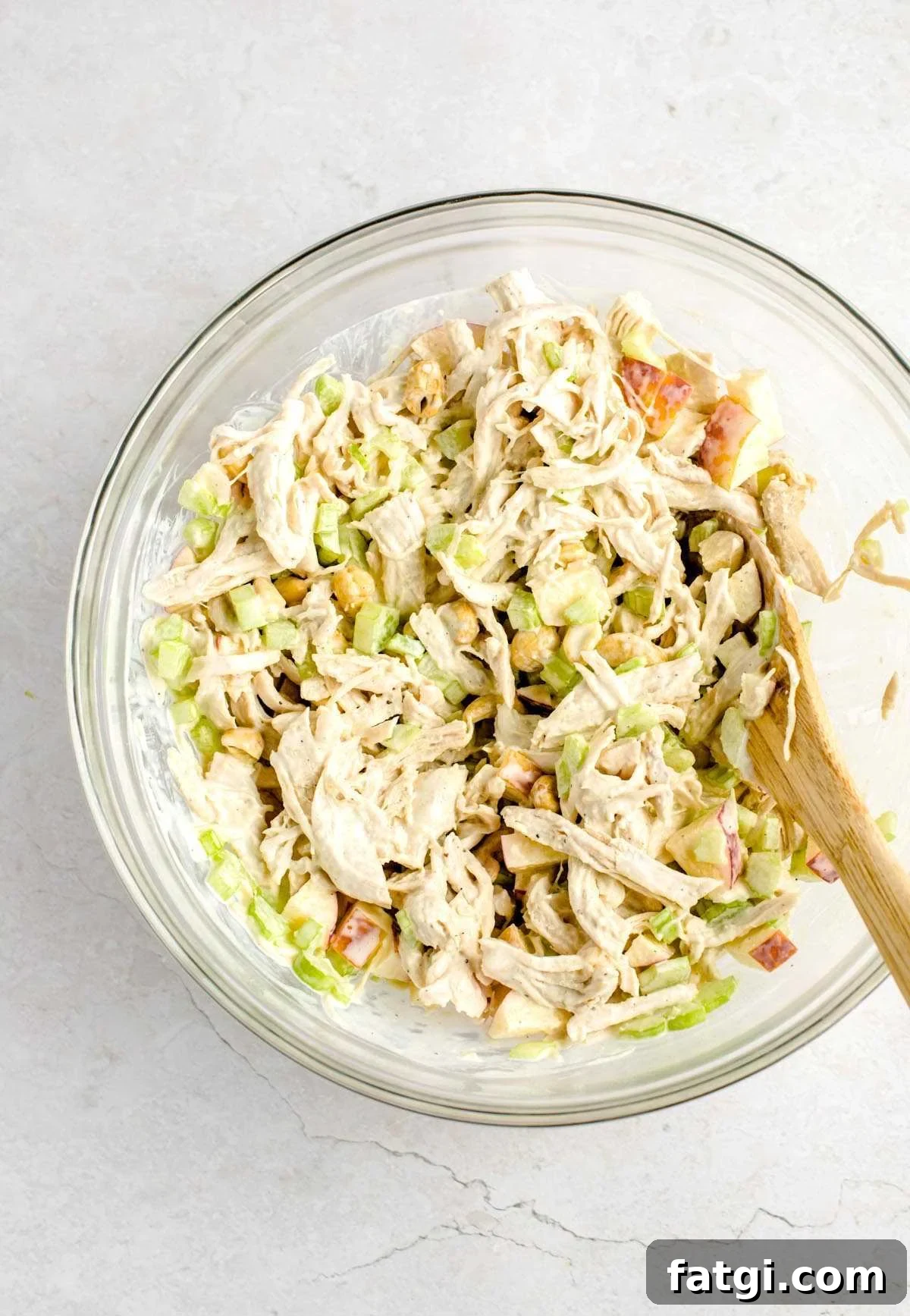 Chicken salad being mixed in a bowl.