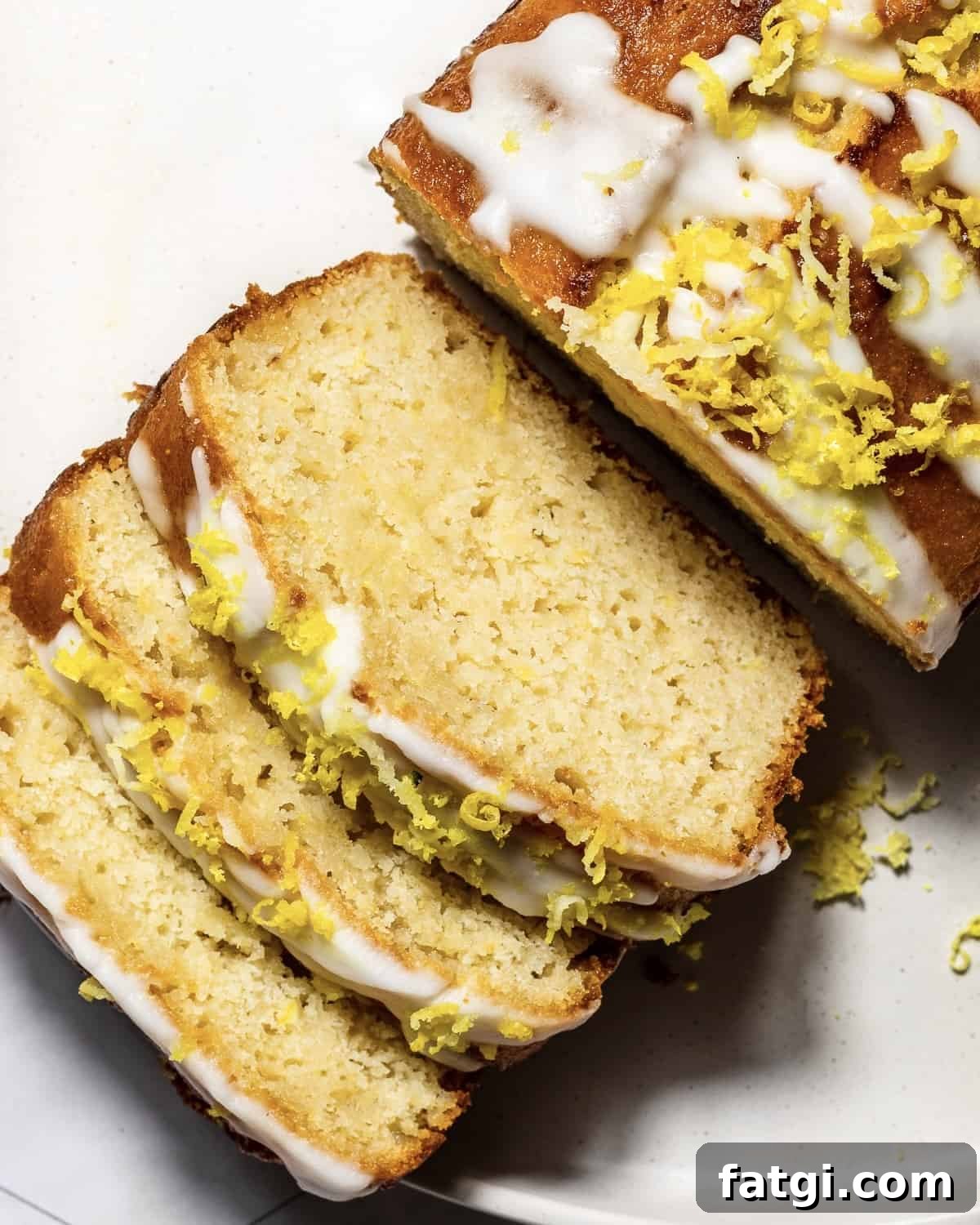 Gluten-Free Lemon Drizzle Loaf Cake Recipe 9 A sliced lemon drizzle loaf cake with lemon icing and lemon zest photographed from above.
