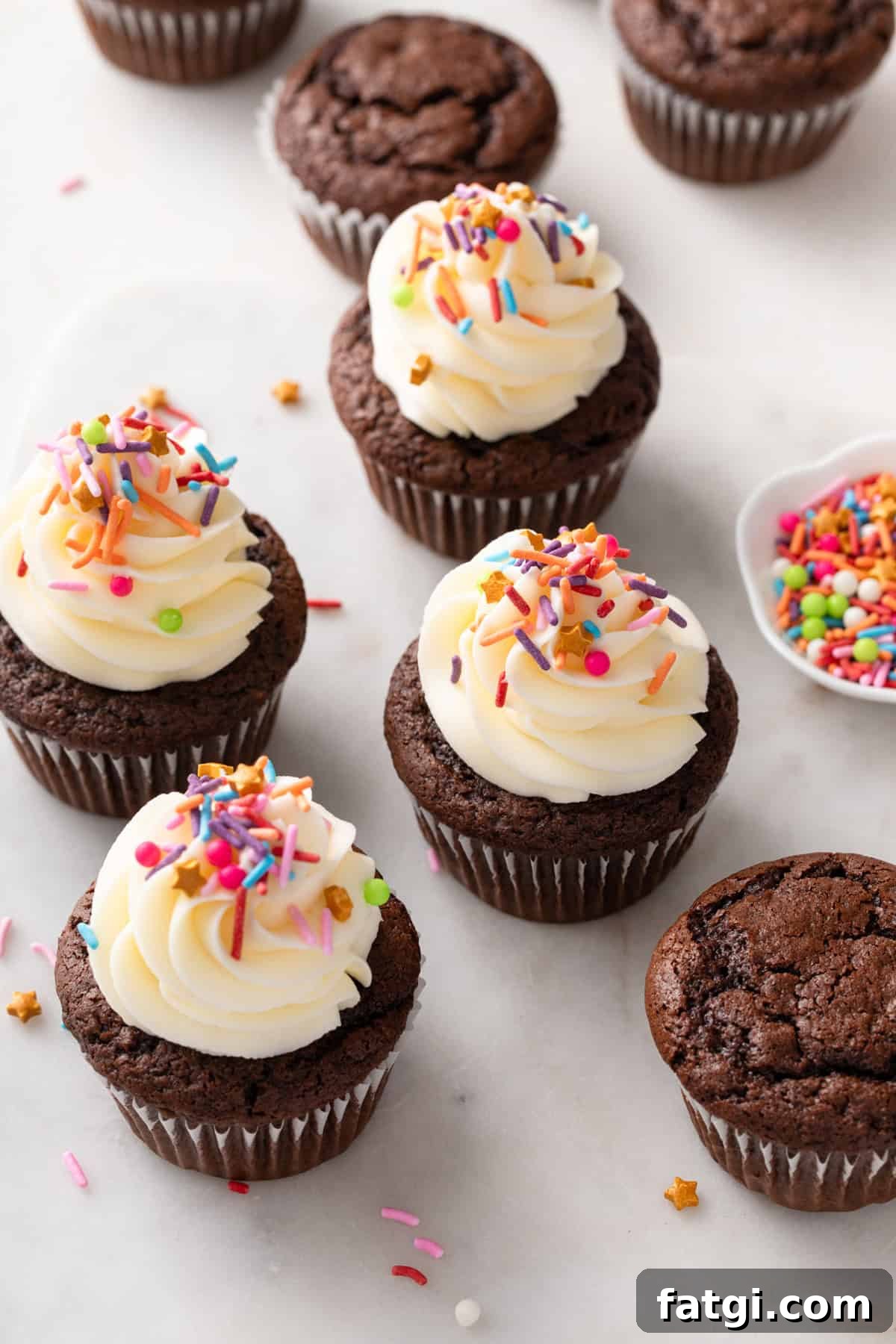 How to Transform Boxed Cake Mix into Gourmet Cakes 2 A mix of frosted and unfrosted chocolate cupcakes scattered on a countertop.