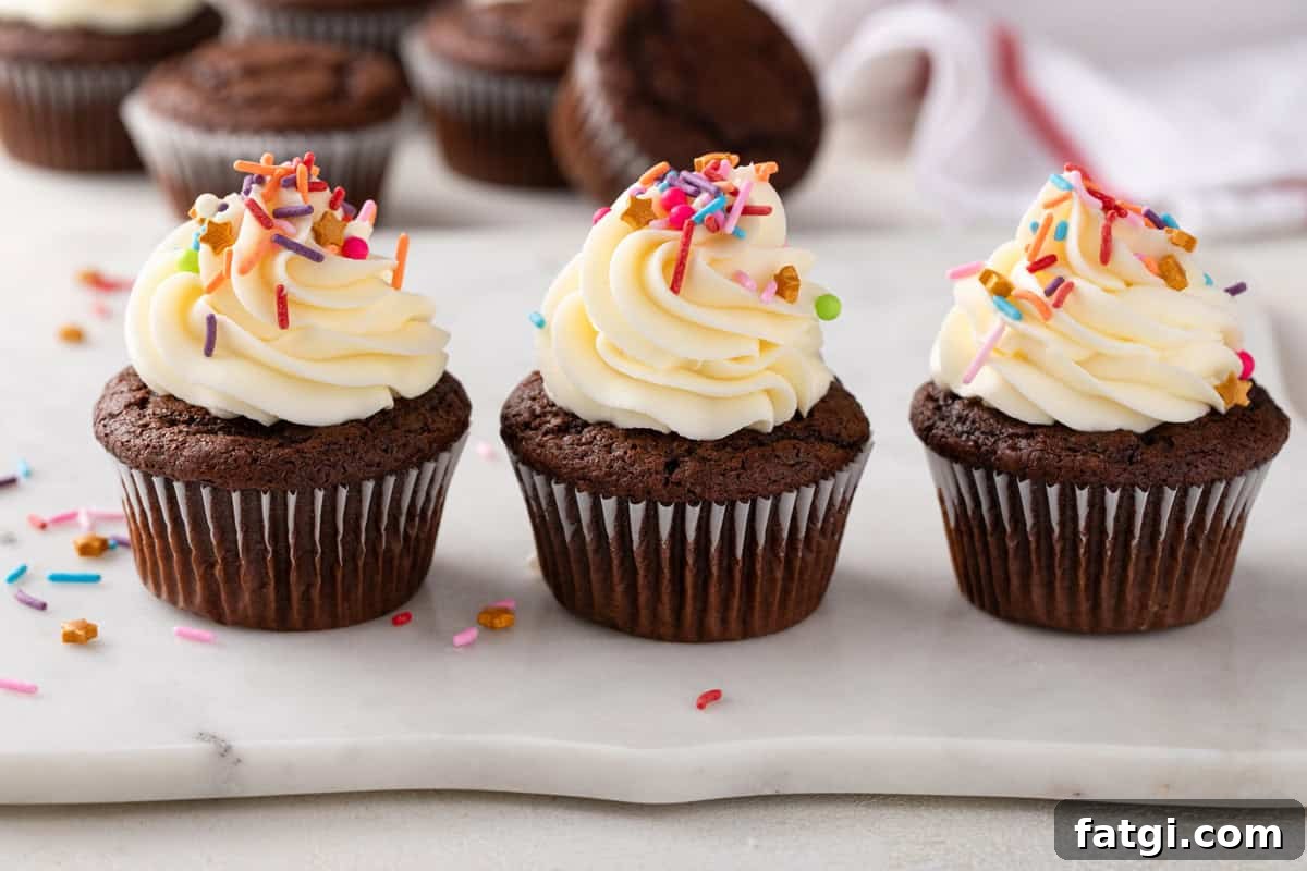 How to Transform Boxed Cake Mix into Gourmet Cakes 9 Three chocolate cupcakes topped with buttercream frosting lined up on a countertop.