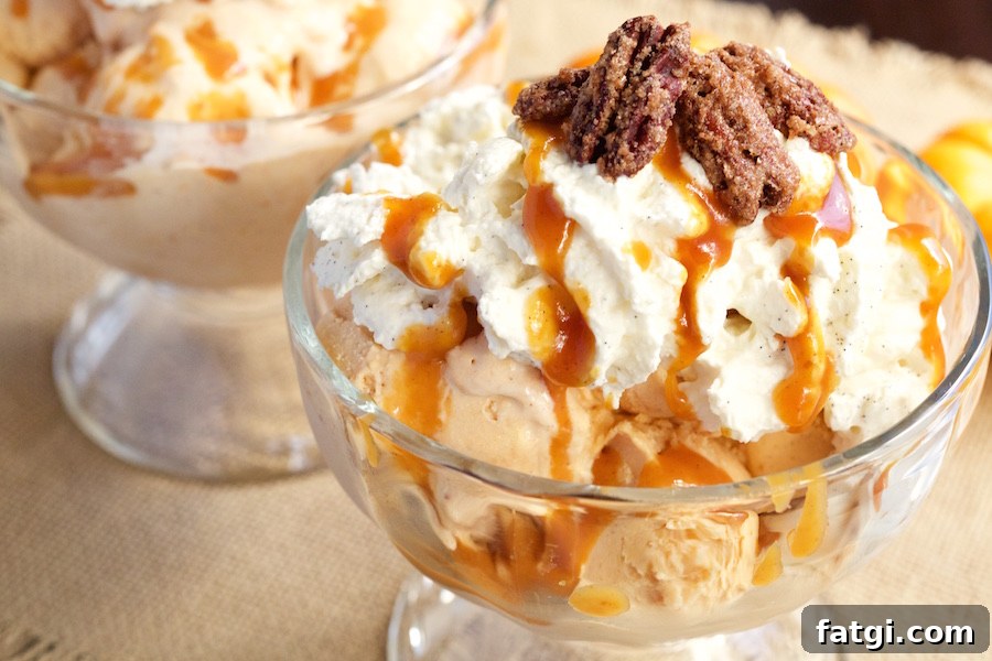 A large glass ice cream sundae bowl filled with Pumpkin Pie Ice Cream Maple Vanilla Bourbon Whipped Cream, Pumpkin Caramel, and Candied Pecans