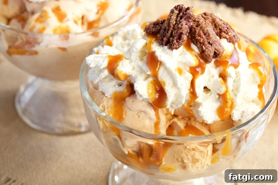 A large glass ice cream sundae bowl filled with Pumpkin Pie Ice Cream Maple Vanilla Bourbon Whipped Cream, Pumpkin Caramel, and Candied Pecans