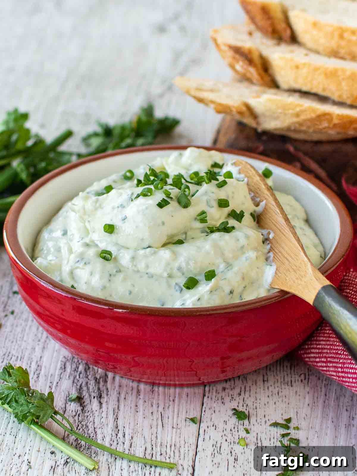 Creamy Homemade Garlic and Herb Cheese Spread Recipe 2 Garlic and herb cheese spread in a red bowl, garnished with chopped chives.