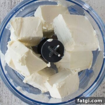 Creamy Homemade Garlic and Herb Cheese Spread Recipe 4 Chunks of cream cheese in a mini food processor viewed from above.