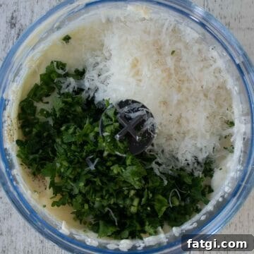 Creamy Homemade Garlic and Herb Cheese Spread Recipe 6 Chopped herbs and grated Parmesan cheese in a mini food processor viewed from above.
