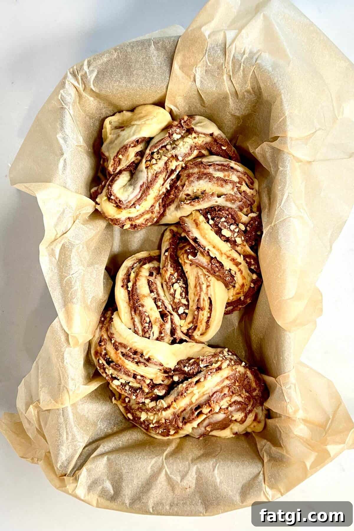 Twisted babka dough and filling into an S shape in parchment lined loaf pan.