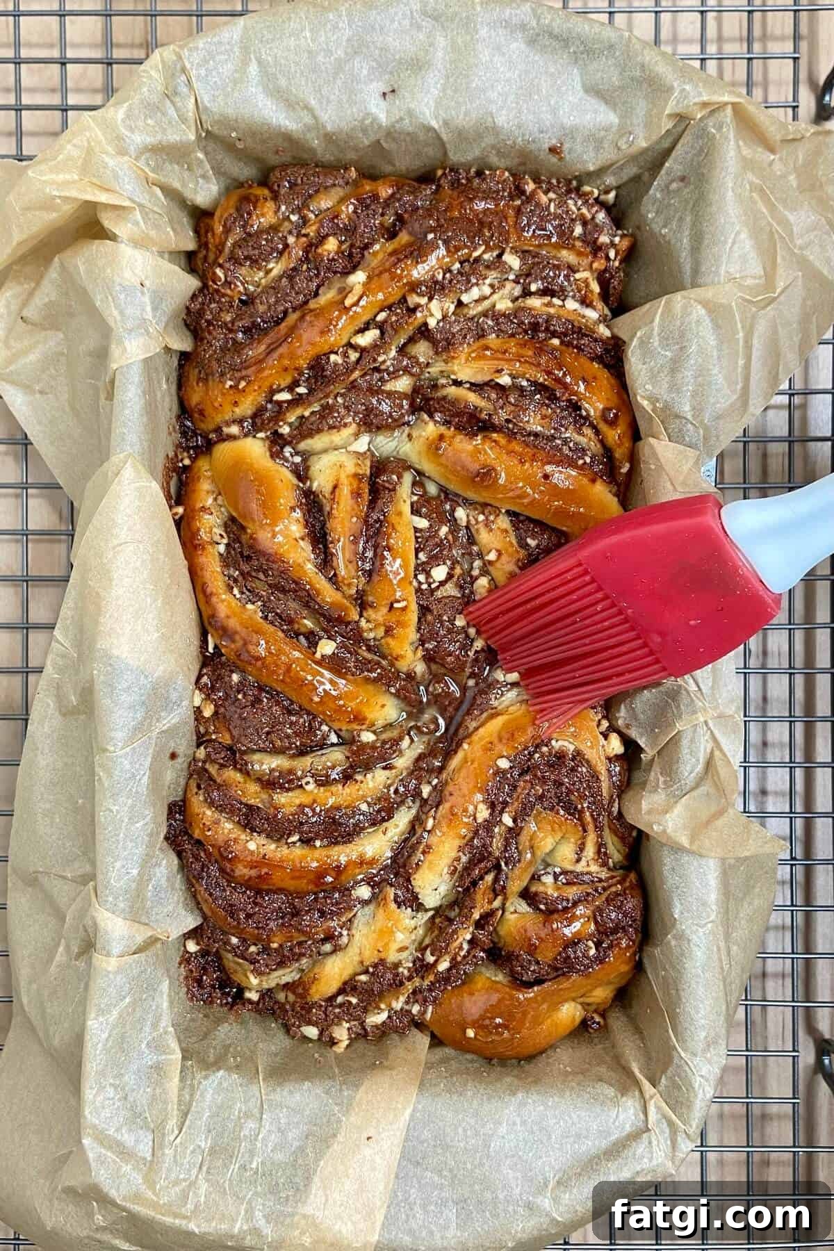 Brushing simple syrup over baked babka, using a silicone brush.