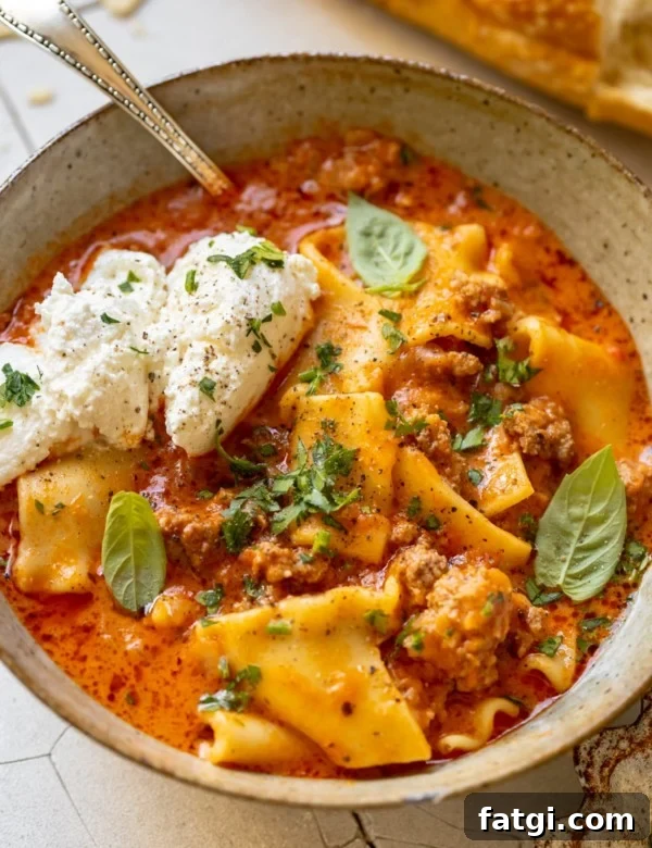 soup made with lasagna noodles in a bowl garnished with ricotta, parsley, basil and parmesan cheese.