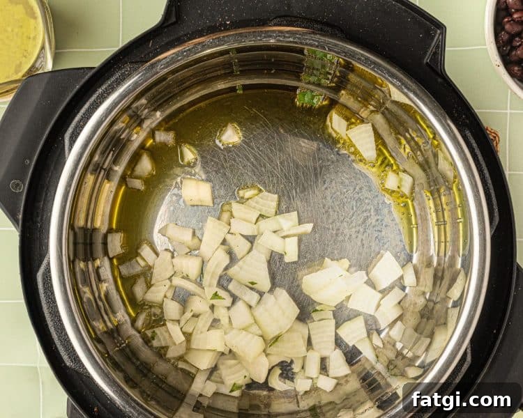 Overhead shot of the inside of an Instant pot with pieces of cut up onion and olive oil.
