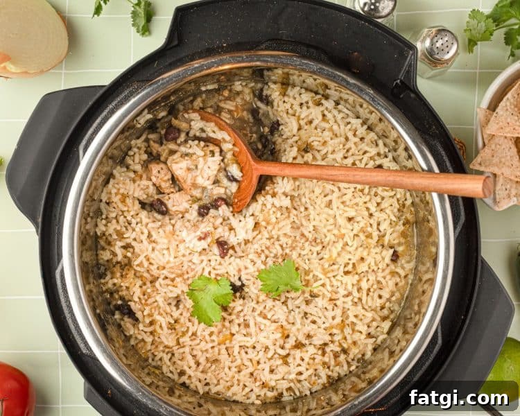 Overhead view of the inside of an instant pot with cooked rice, chicken, black beans, and spices, and wooden spoon pulling out a small serving.