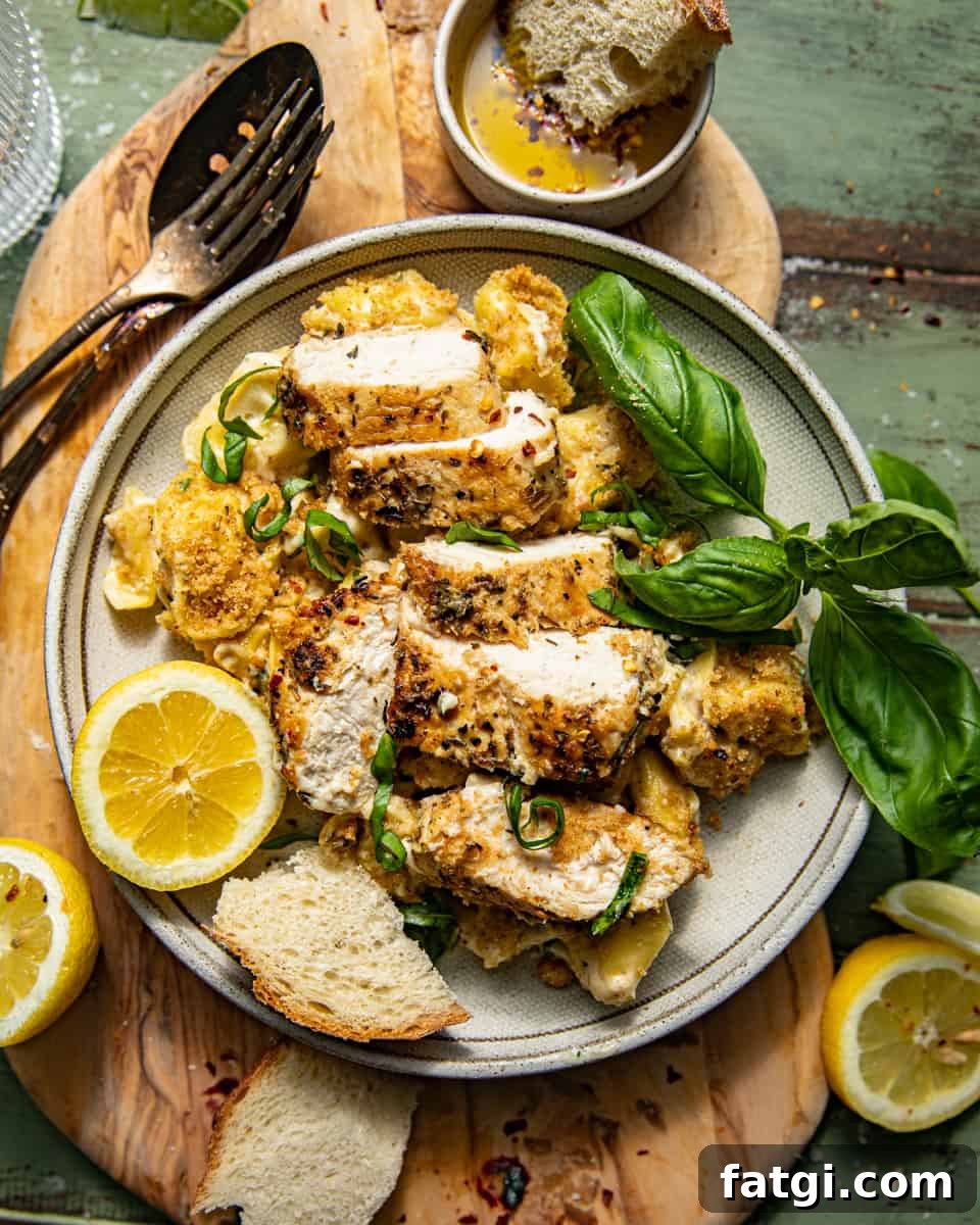 asiago tortelloni alfredo with grilled chicken on a plate garnished with lemon wedges and fresh basil.