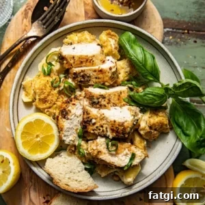 asiago tortelloni alfredo with grilled chicken on a plate garnished with lemon wedges and fresh basil.