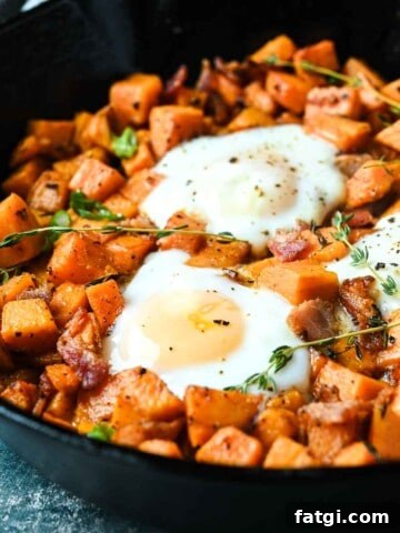 Close-up of sweet potatoes and bacon hash in a skillet with thyme sprigs on top.