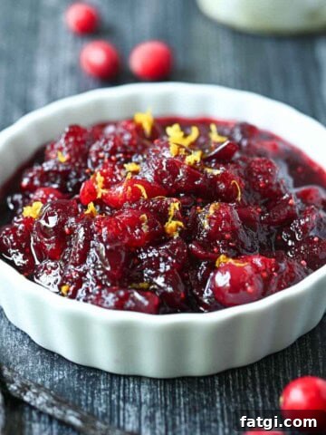 Close-up of cranberry compote in a white bowl with orange zest.