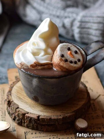 Malted milk hot chocolate in a grey mug with whipped cream and snowman marshmallows.