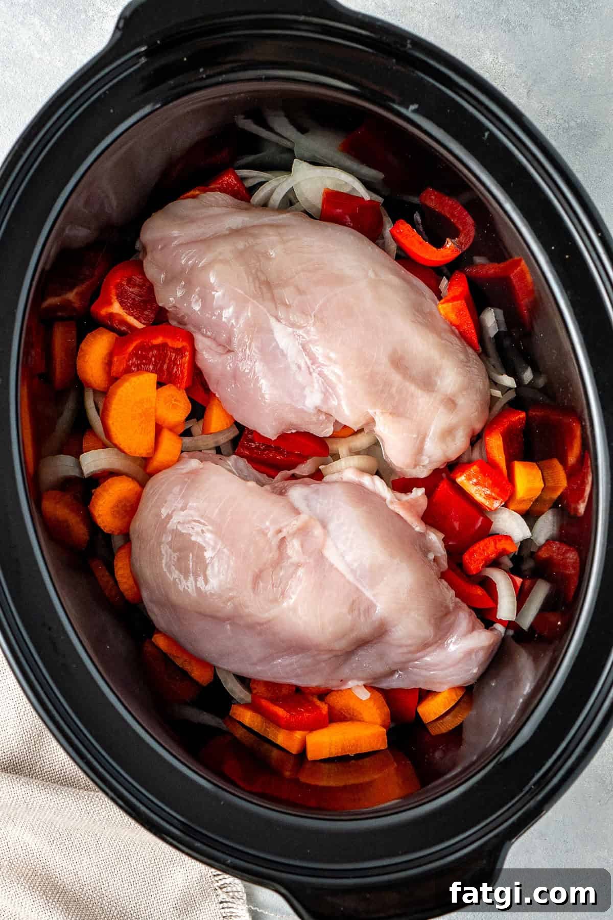 The onion, carrot, capsicum and chicken breast in the slow cooker.