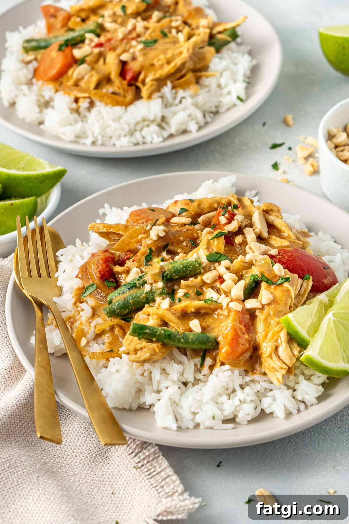 Satay chicken with rice and fresh lime served on a plate with cultlery.