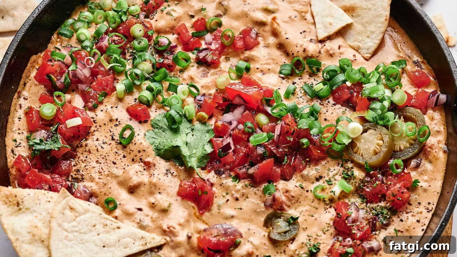 21 Pork Dinner Recipes for When You Need More on the Table 18 A skillet filled with creamy cheese dip topped with chopped tomatoes, green onions, cilantro, and sliced jalapeños, surrounded by triangular tortilla chips.