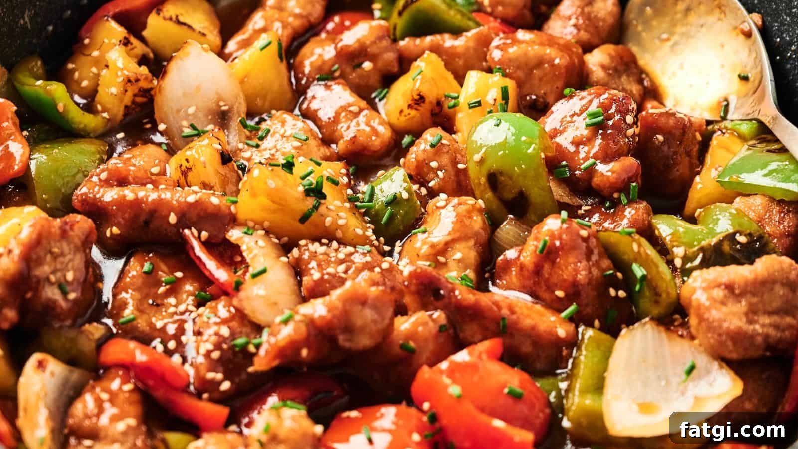 21 Pork Dinner Recipes for When You Need More on the Table 21 Close-up of sweet and sour pork with chunks of bell peppers, onions, and pineapple, garnished with sesame seeds and chives.