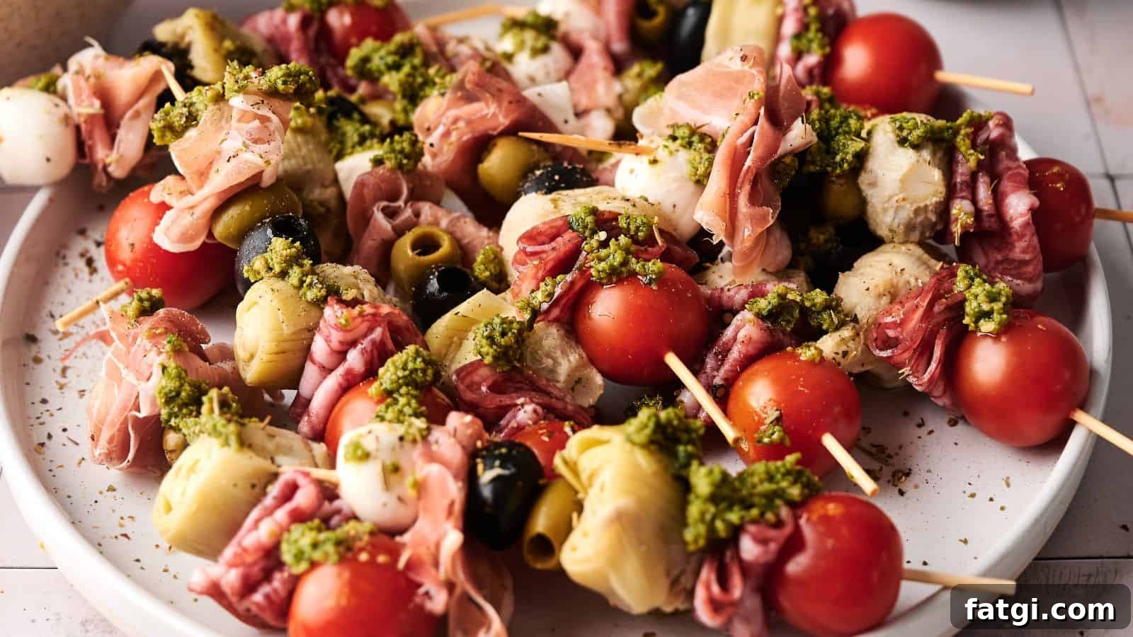 21 Pork Dinner Recipes for When You Need More on the Table 8 A plate of antipasto skewers with cherry tomatoes, mozzarella, olives, artichoke hearts, cured meats, and a drizzle of green pesto.