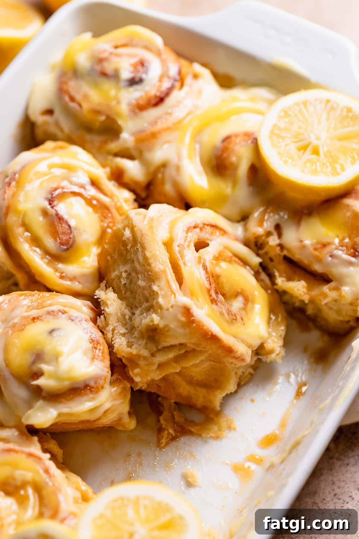 Lemon rolls with lemon curd in a white baking dish.