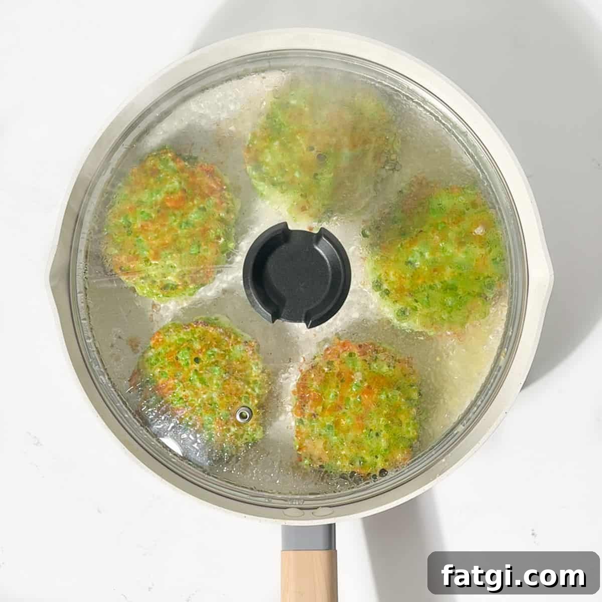 Cheesy Green Pea Fritters Recipe 11 Frying the green pea fritters in a large frying pan with the lid on.