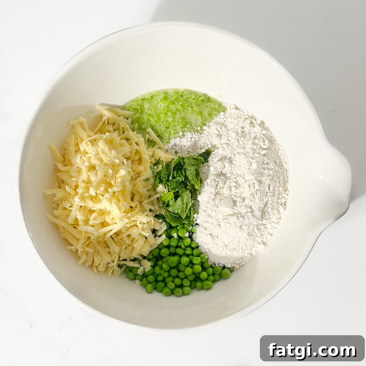 Cheesy Green Pea Fritters Recipe 8 Adding all the ingredients for the green pea fritters in a large white bowl.