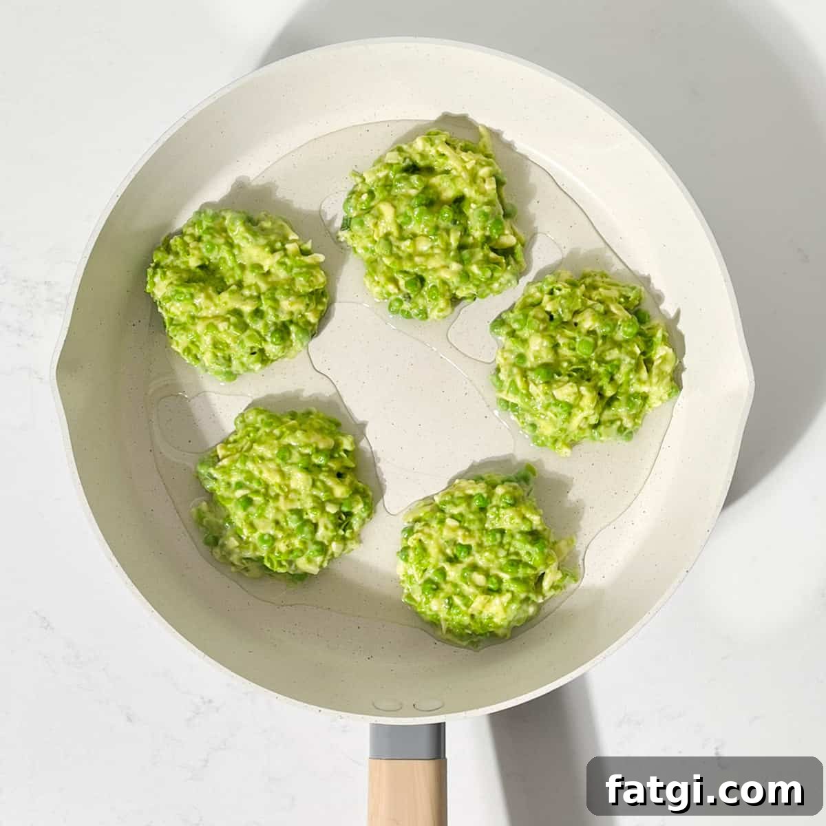 Cheesy Green Pea Fritters Recipe 10 Scooping dollops of the pea mixture in a large frying pan.