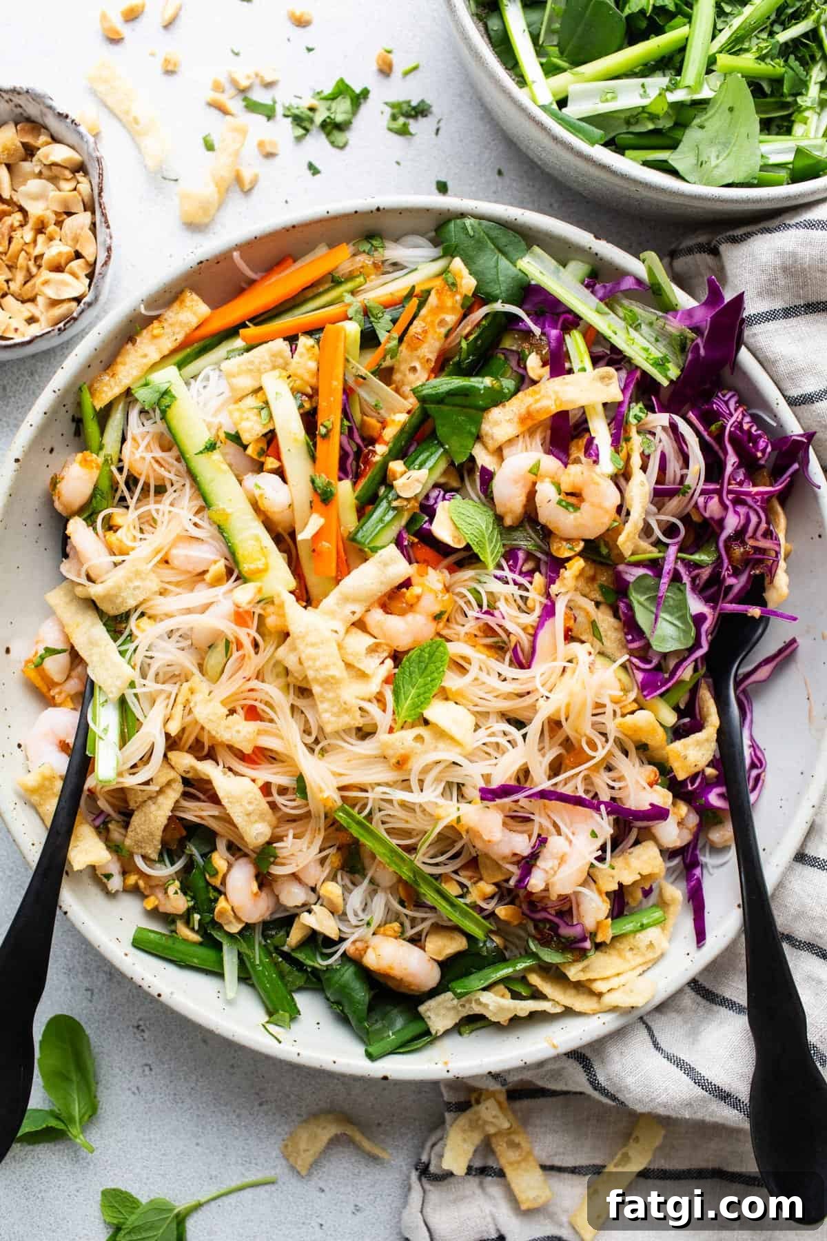 A bowl of asian noodle salad with peanuts and vegetables.