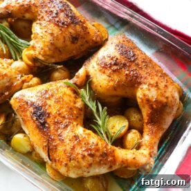 Baked chicken leg quarters with crispy skin and roasted baby potatoes garnished with rosemary.