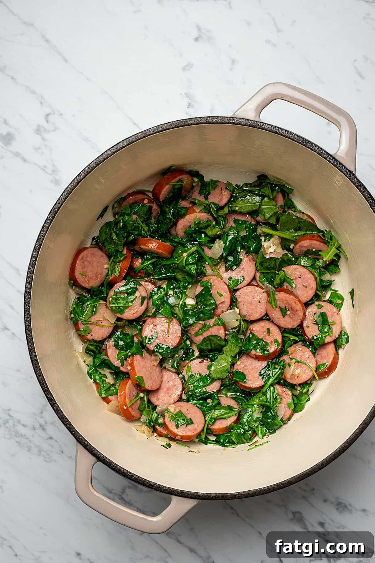 Sausage, kale, and potato soup ingredients cooking in a soup pot.
