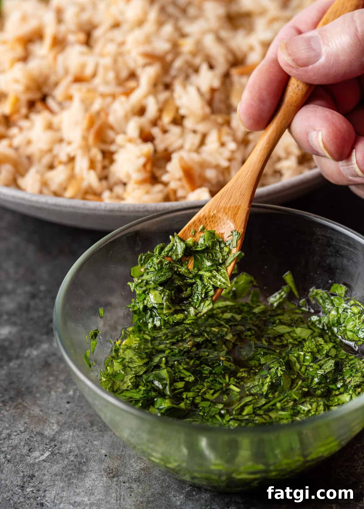 closeup: a wooden spoon stirring my lemon mint sauce in a small glass bowl