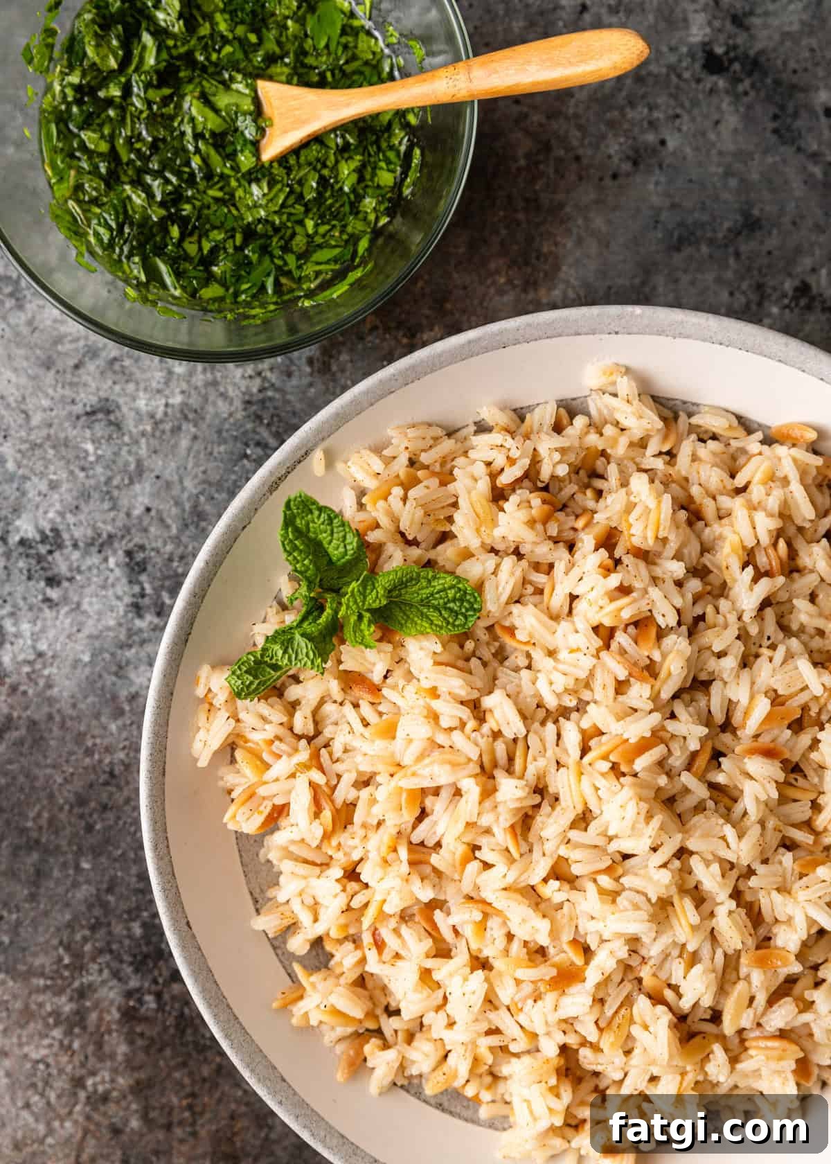 overhead: a serving bowl full of my orzo rice recipe with a bowl of lemon mint sauce to the side