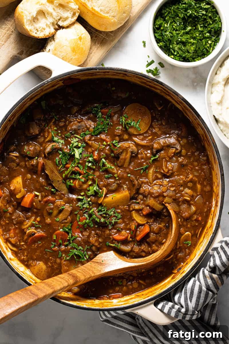 Large white pot filled with vegan lentil stew garnished with fresh parsley 