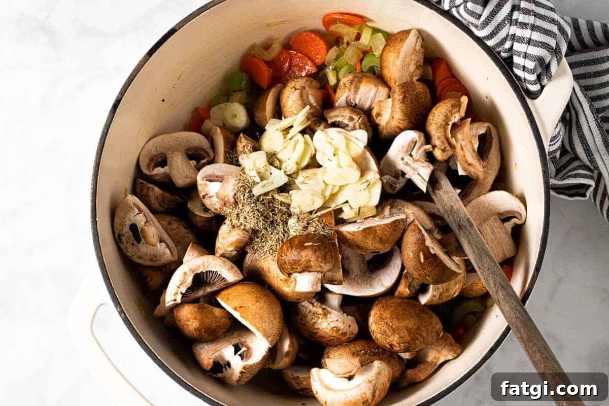 Large white pot filled with chopped veggies sliced garlic and dried herbs