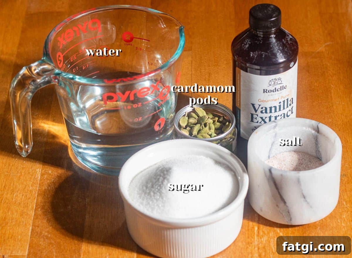Homemade Cardamom Syrup Recipe for Coffee and Cocktails 4 Overhead shot of cardamom syrup ingredients including sugar, water, cardamom pods, vanilla extract, and salt on a wooden surface.