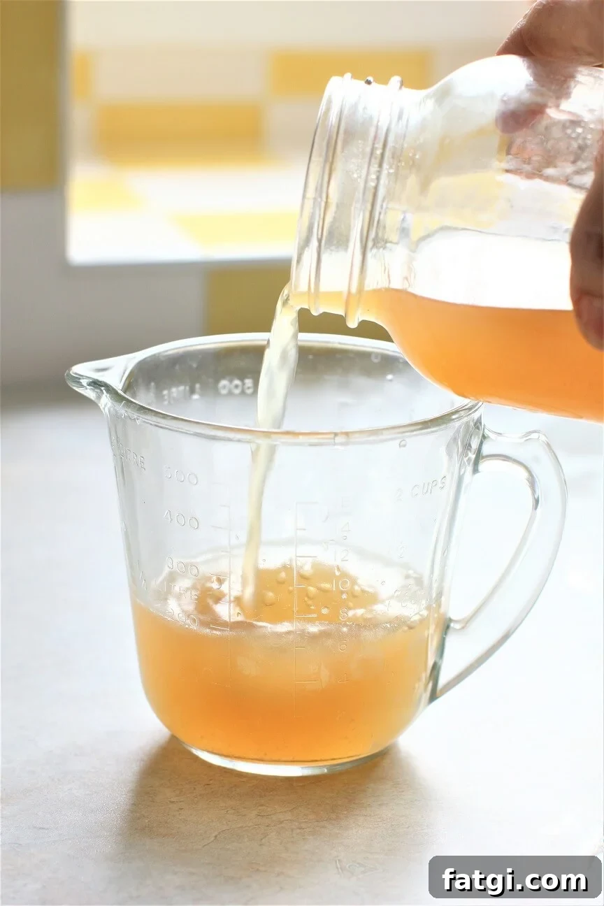 pouring chicken stock into a measuring cup