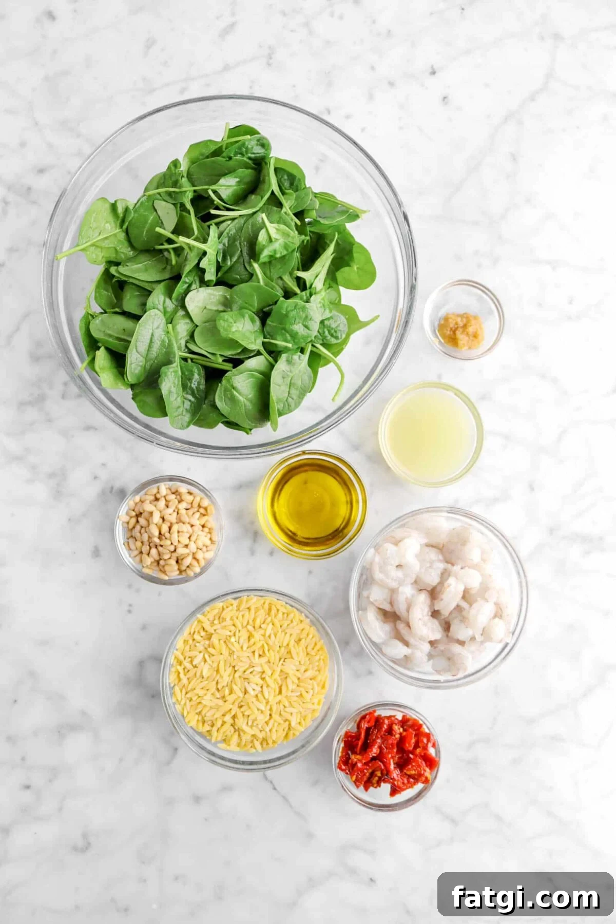 spinach, garlic, lemon juice, olive oil, pine nuts, orzo, raw shrimp, and sun-dried tomatoes in bowls