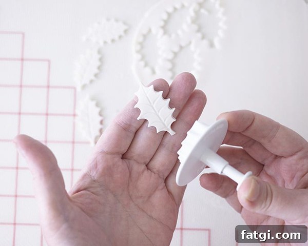 Cutting white fondant holly leaves with plunger cutter