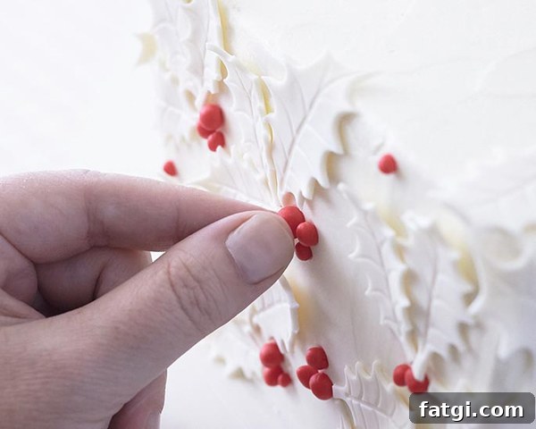 Fondant holly leaves and berries on gift box cake