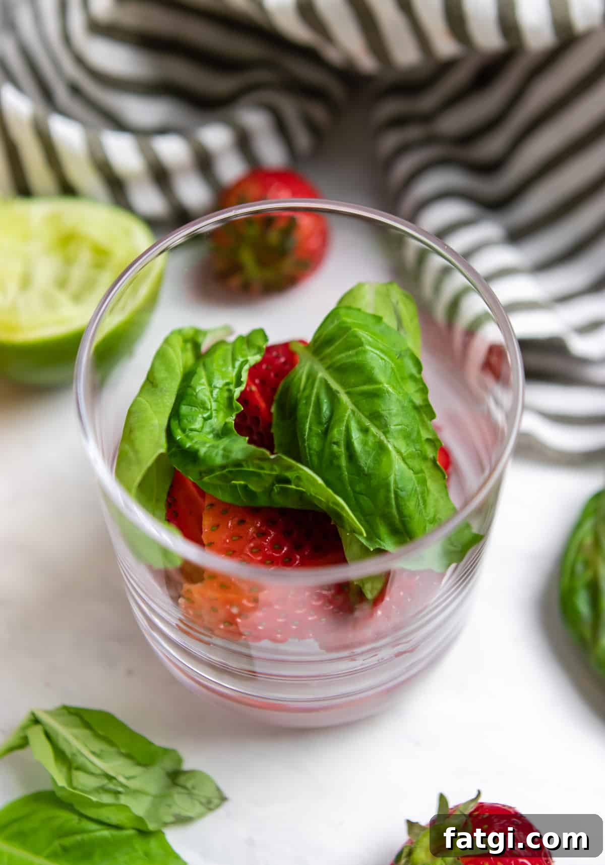 Strawberries and basil in glass before muddling.