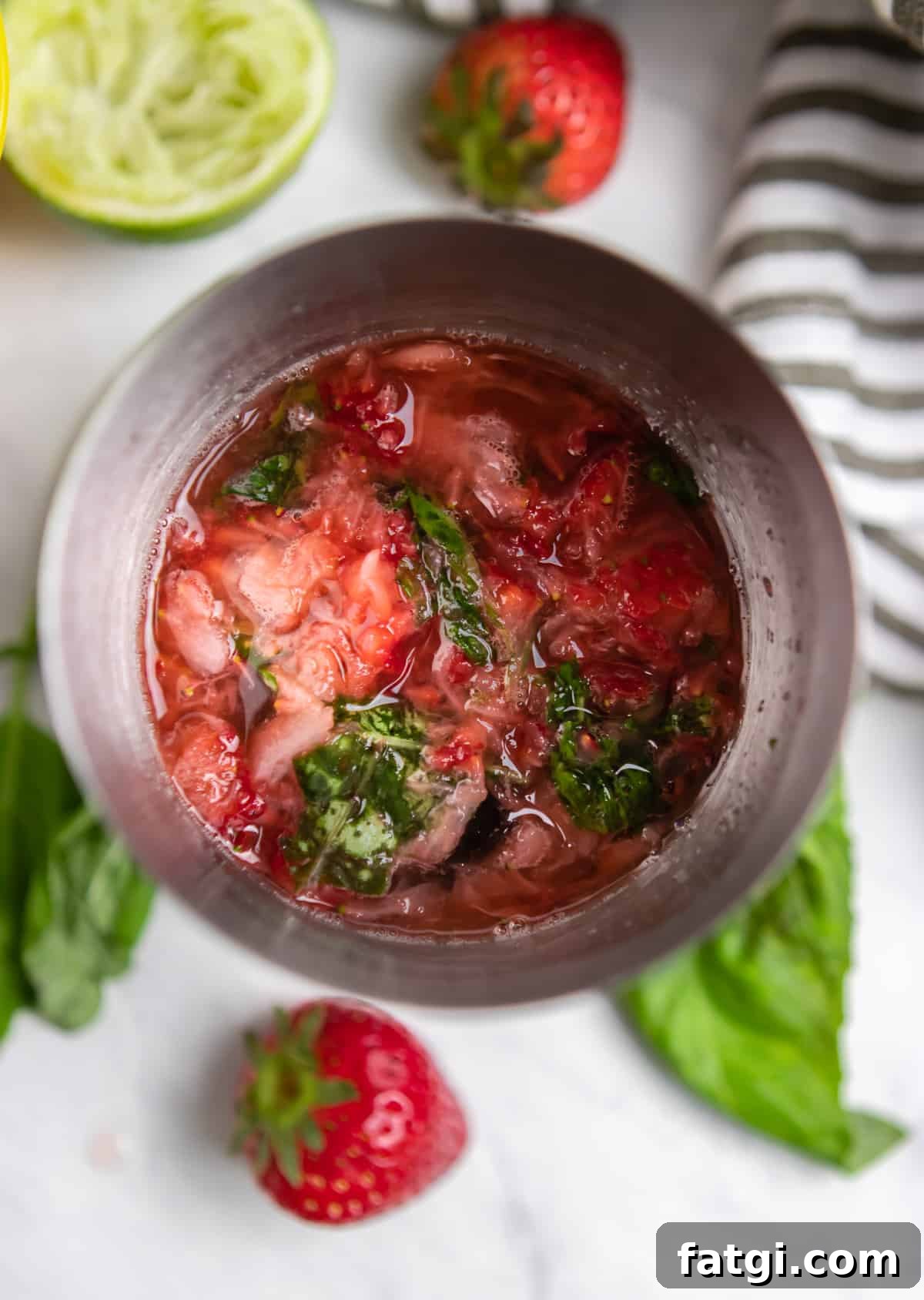 Strawberry basil margarita ingredients in cocktail mixer.