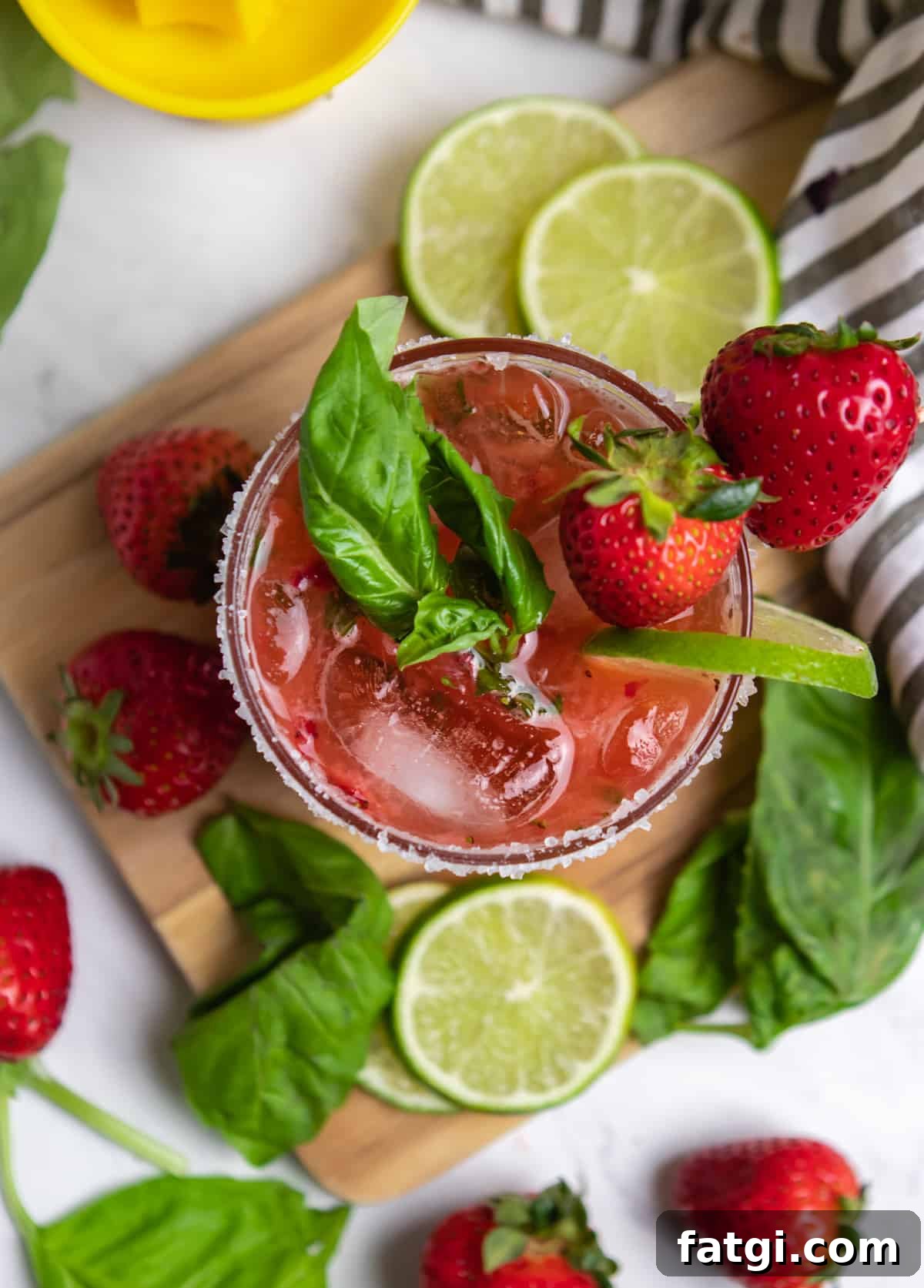 Overhead view of glass with strawberry margarita with fresh basil leaves.