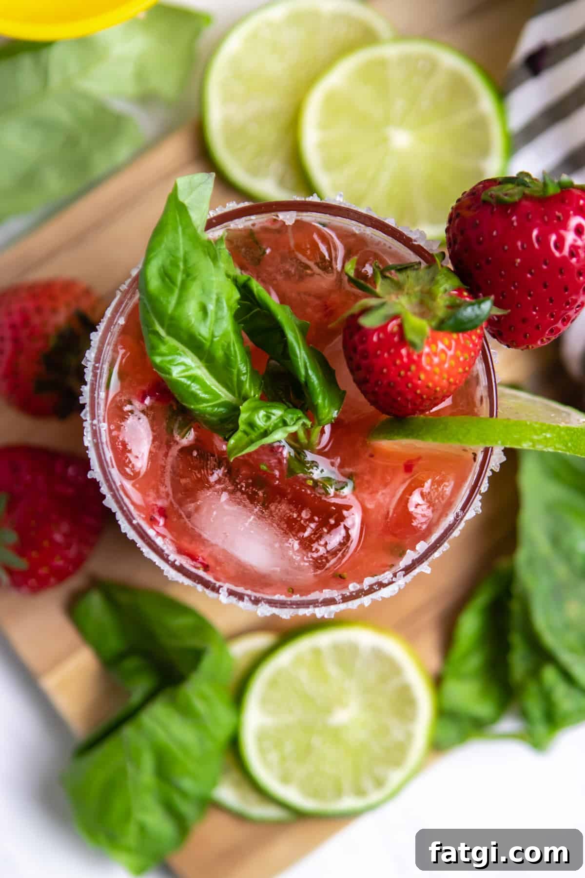 Overhead view of strawberry margarita with basil, lime and strawberry garnish.