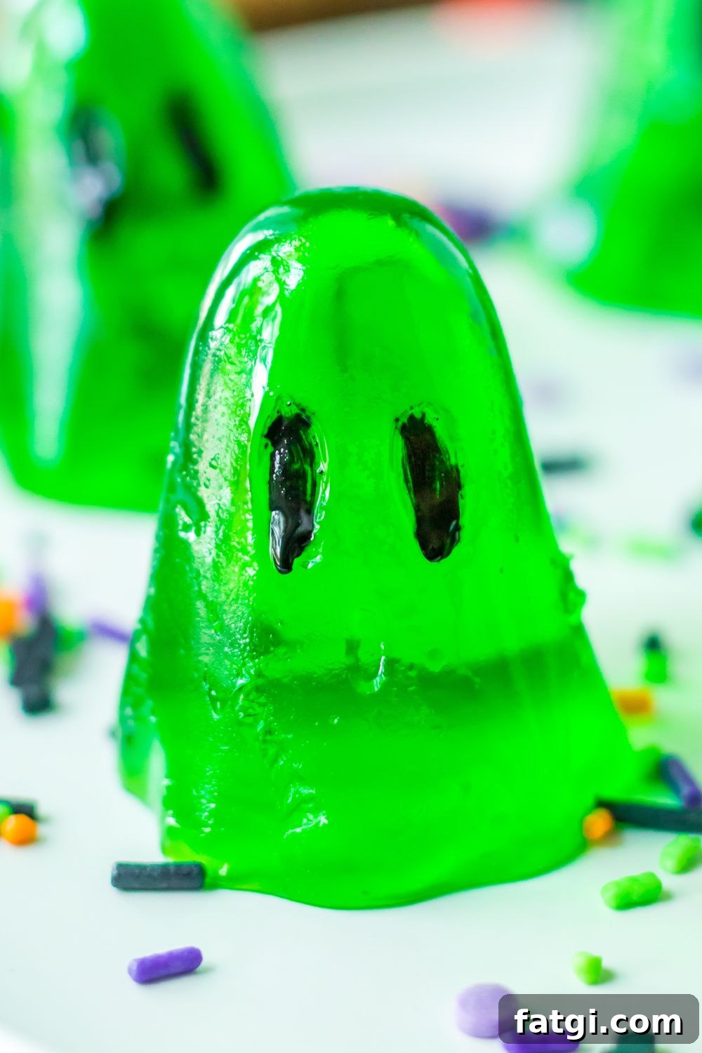 Ghost Jello Shots for Halloween Parties 3 ghost shaped jello shots on table with sprinkles
